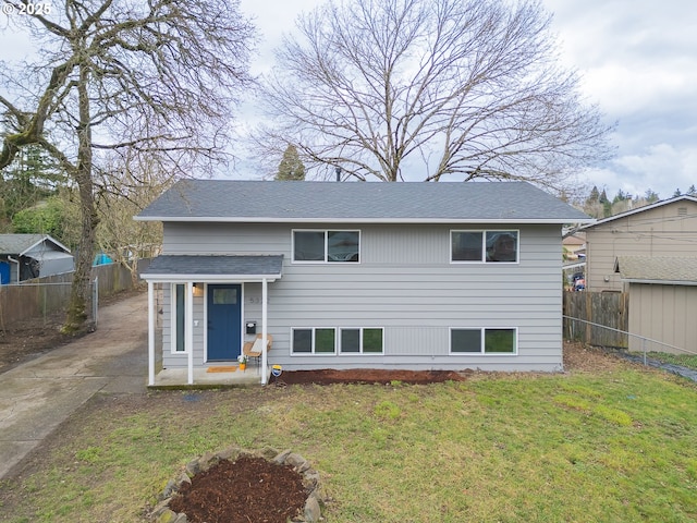 view of front of property with a front yard, fence, and a shingled roof