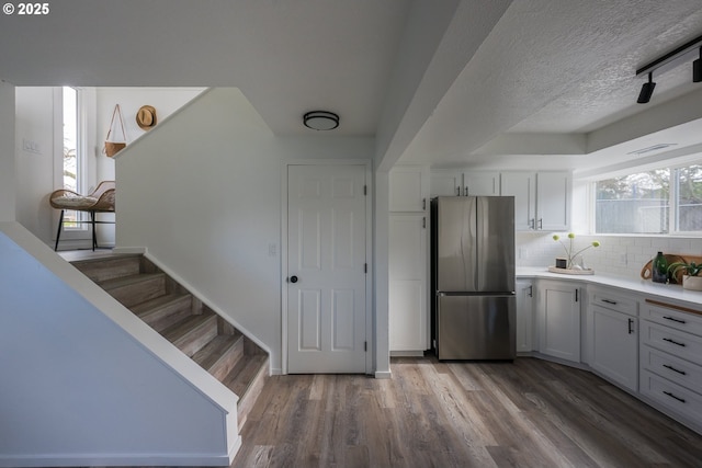 kitchen featuring wood finished floors, white cabinets, light countertops, backsplash, and freestanding refrigerator