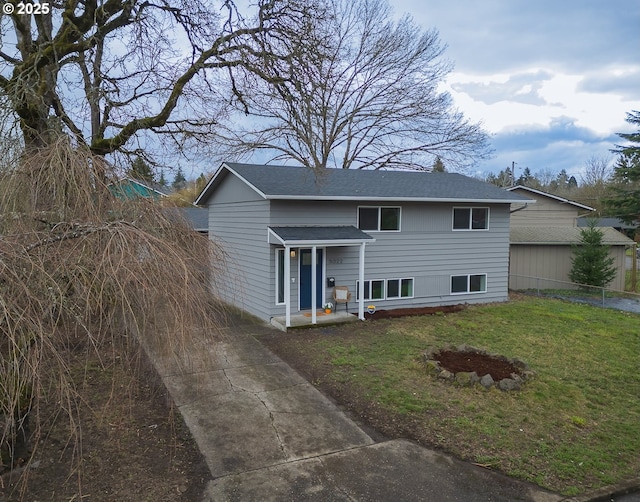 view of front of home featuring a shingled roof, a front yard, and fence