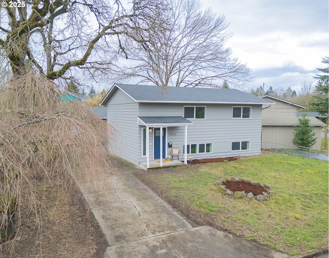 view of front of home with a front lawn, fence, and a shingled roof