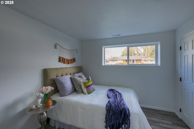 bedroom featuring wood finished floors, visible vents, and baseboards