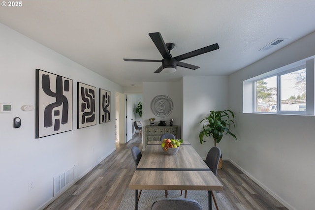 dining area featuring dark wood-type flooring, visible vents, ceiling fan, and baseboards