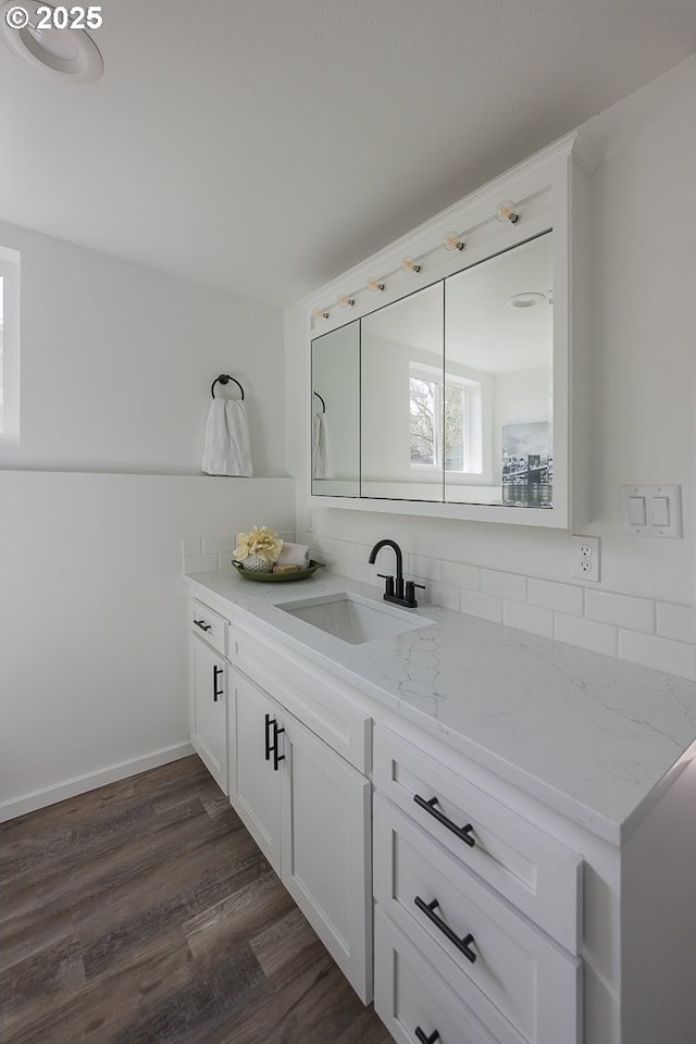 bathroom with tasteful backsplash, baseboards, wood finished floors, and vanity