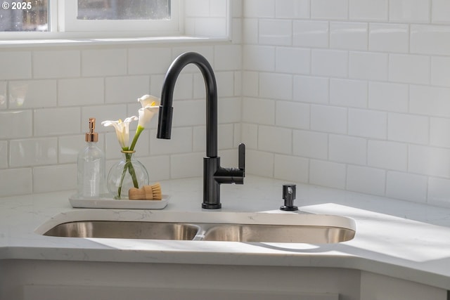 room details with tasteful backsplash, a sink, and light stone counters