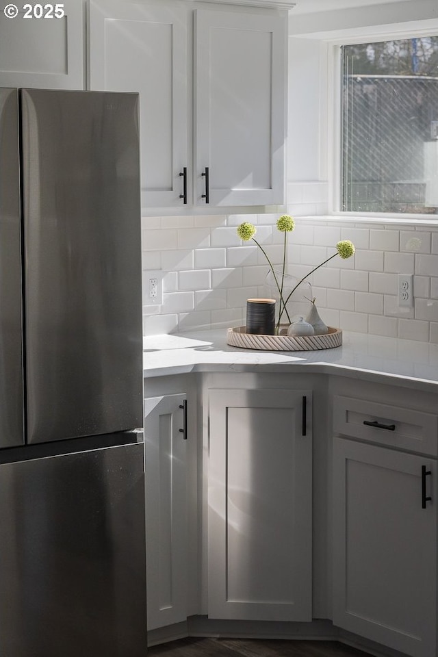 kitchen with light countertops, backsplash, and freestanding refrigerator