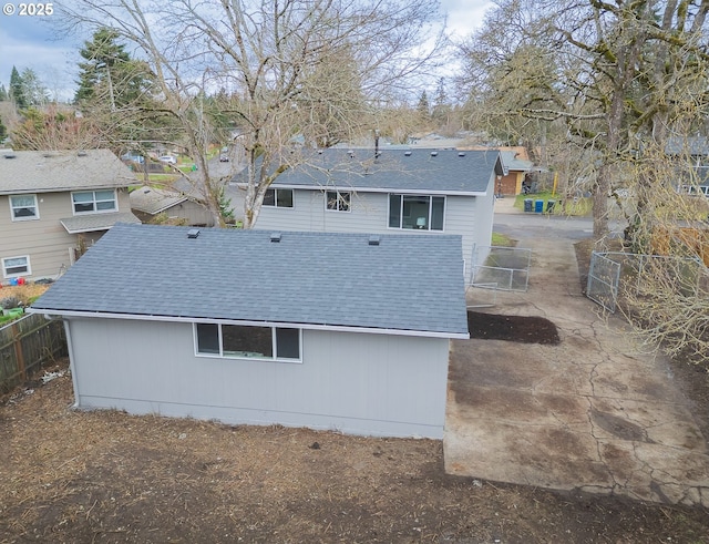 exterior space featuring a shingled roof and fence