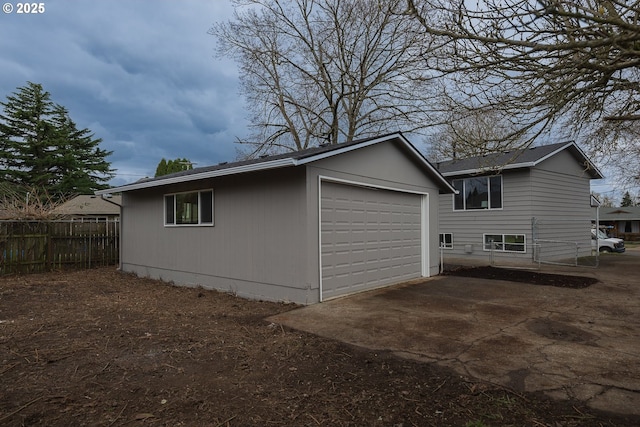 view of side of property with an outdoor structure, fence, and a detached garage