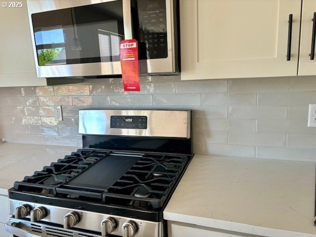 1747 N Millican Creek St, Lafayette, OR 97127 - kitchen view of appliances with stainless steel finishes, backsplash, white cabinetry, and light stone countertops