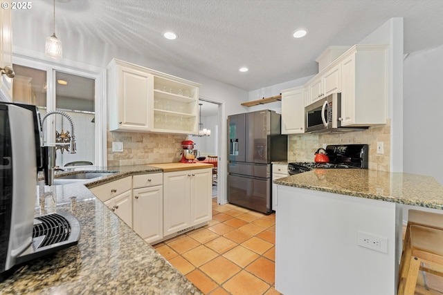 kitchen with appliances with stainless steel finishes, a sink, open shelves, a peninsula, and tasteful backsplash