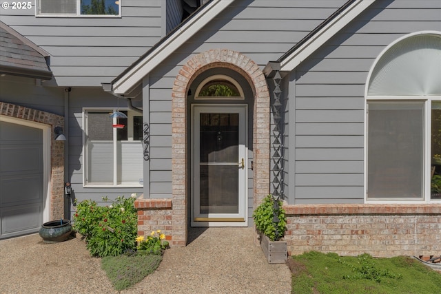 view of exterior entry featuring brick siding and a garage