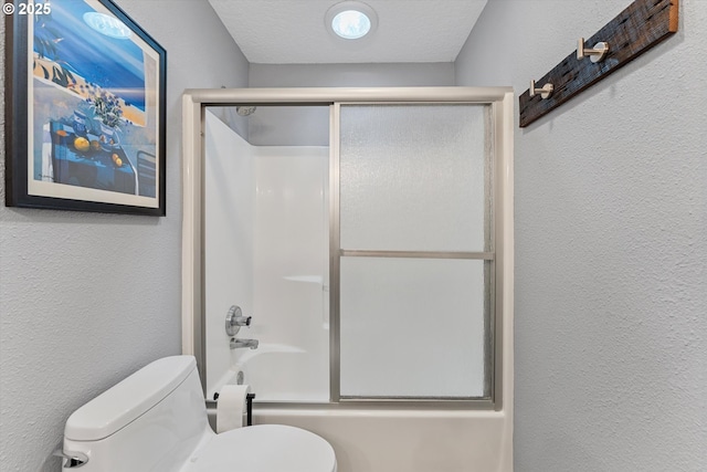 full bath with a textured wall, toilet, and enclosed tub / shower combo