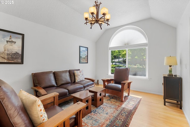living area featuring lofted ceiling, light wood-style flooring, a chandelier, a textured ceiling, and baseboards