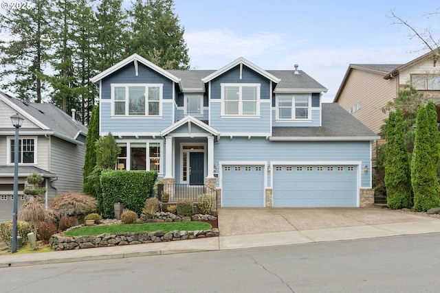 craftsman inspired home featuring a shingled roof and concrete driveway