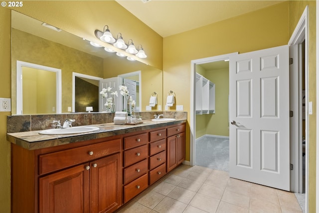 bathroom with double vanity, tile patterned flooring, a sink, and baseboards