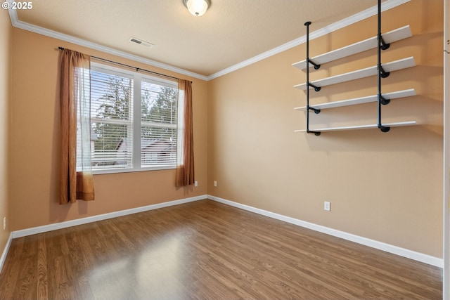 unfurnished room with visible vents, crown molding, baseboards, and wood finished floors