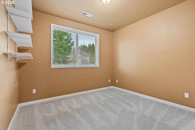 unfurnished room with carpet floors, visible vents, and baseboards