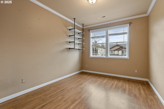 unfurnished dining area with visible vents, baseboards, crown molding, and wood finished floors