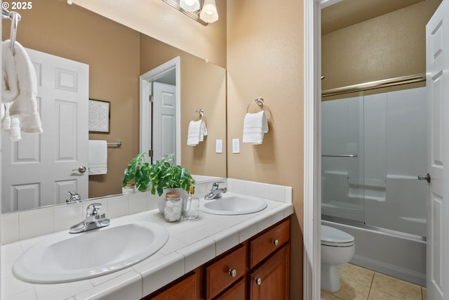 bathroom featuring toilet, tile patterned flooring, double vanity, and a sink