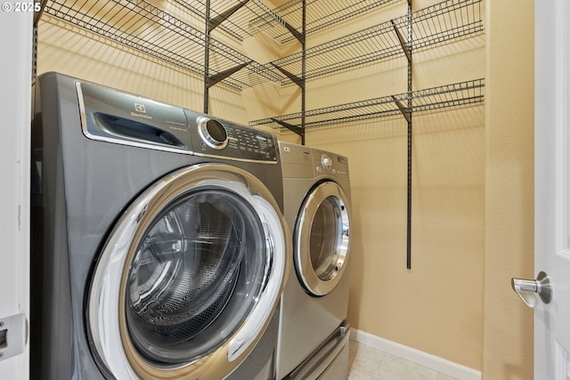 laundry area with laundry area, washer and clothes dryer, baseboards, and light tile patterned floors