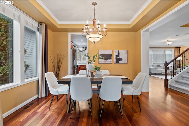 dining space with a tray ceiling, stairway, and wood finished floors