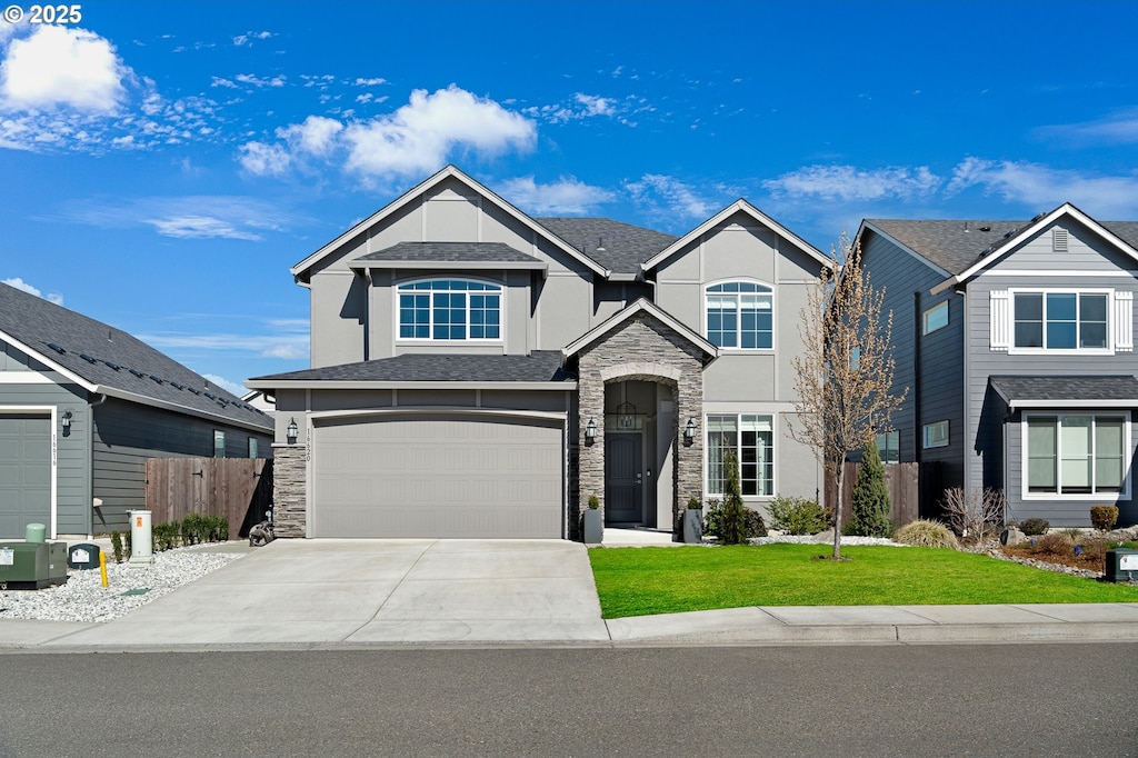 view of front facade featuring stucco siding, driveway, stone siding, fence, and a garage