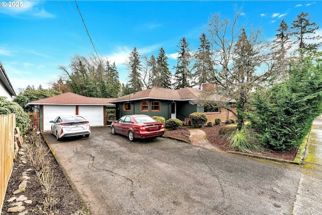 single story home featuring a garage, fence, a chimney, and an outdoor structure