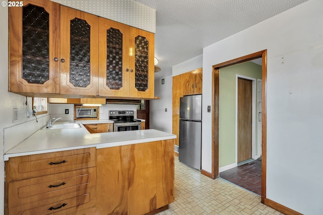 kitchen featuring baseboards, stainless steel appliances, light countertops, under cabinet range hood, and a sink