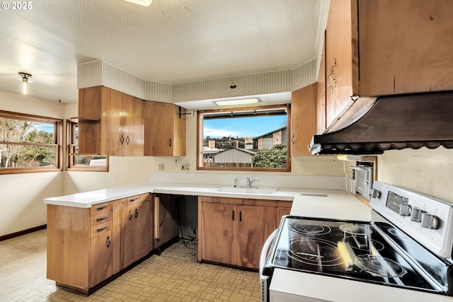 kitchen with light countertops, electric range, brown cabinetry, and a sink