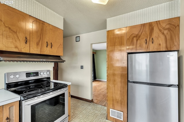 kitchen with under cabinet range hood, stainless steel appliances, visible vents, baseboards, and brown cabinets