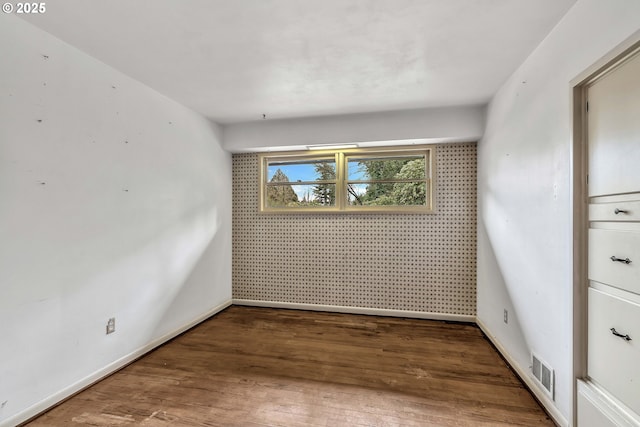 spare room featuring baseboards, visible vents, and wood finished floors