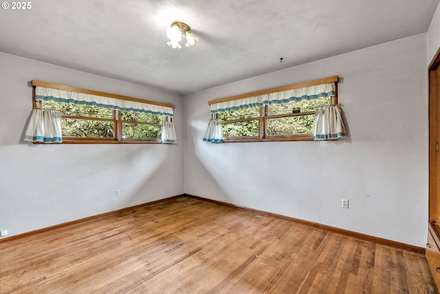 empty room with hardwood / wood-style flooring and baseboards