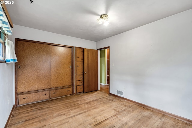 unfurnished bedroom featuring wood-type flooring, visible vents, and baseboards