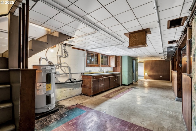 kitchen with glass insert cabinets, electric water heater, and concrete block wall