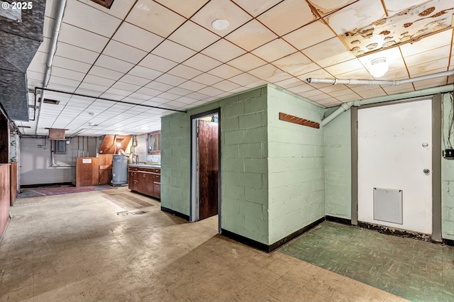 interior space with gas water heater, concrete block wall, and tile patterned floors