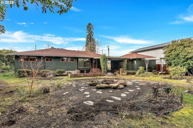 back of property featuring an outdoor fire pit and fence