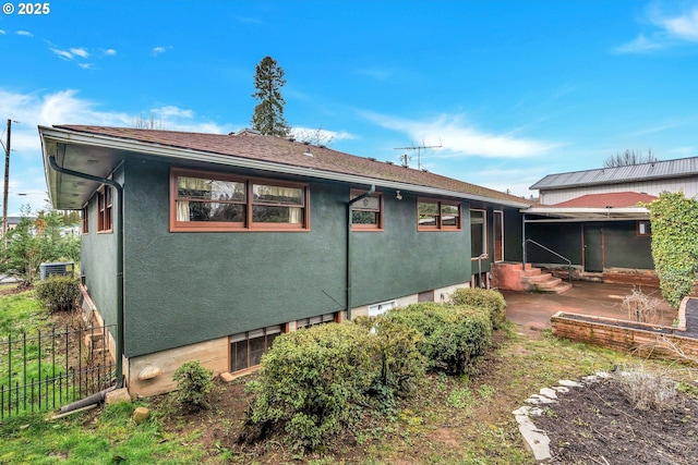 rear view of property featuring entry steps, a patio area, fence, and stucco siding