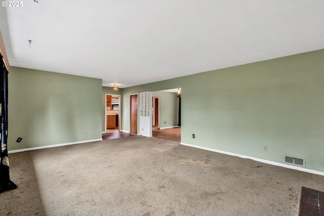 carpeted spare room featuring visible vents and baseboards