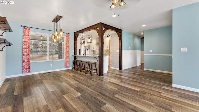 unfurnished dining area featuring ceiling fan, dark wood-type flooring, a sink, visible vents, and baseboards