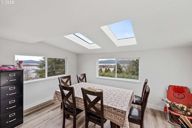546 W Fir Ave, Coos Bay, OR 97420 - dining room featuring lofted ceiling with skylight, plenty of natural light, light wood-style floors, and baseboards