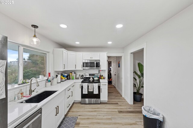 546 W Fir Ave, Coos Bay, OR 97420 - kitchen with light wood-type flooring, a sink, tasteful backsplash, appliances with stainless steel finishes, and light countertops
