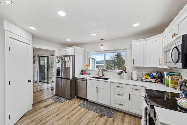 546 W Fir Ave, Coos Bay, OR 97420 - kitchen featuring light wood finished floors, a sink, decorative backsplash, stainless steel appliances, and white cabinetry