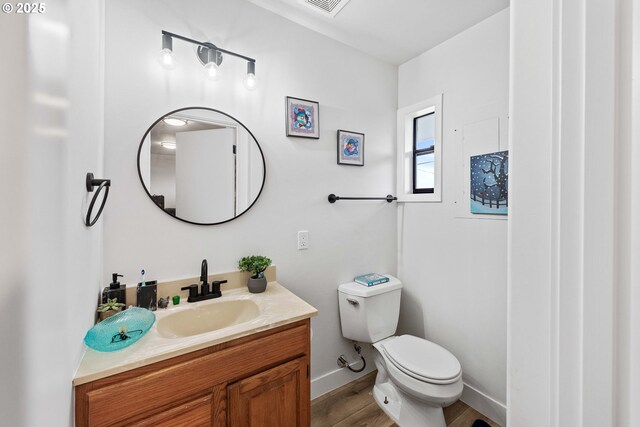 546 W Fir Ave, Coos Bay, OR 97420 - bathroom with visible vents, toilet, wood finished floors, baseboards, and vanity