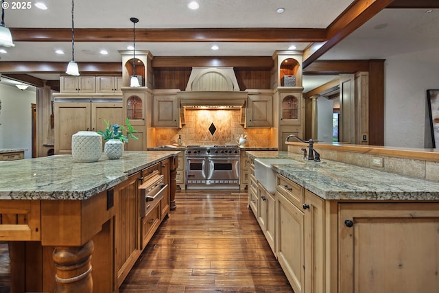 kitchen featuring a spacious island, sink, tasteful backsplash, pendant lighting, and range with two ovens