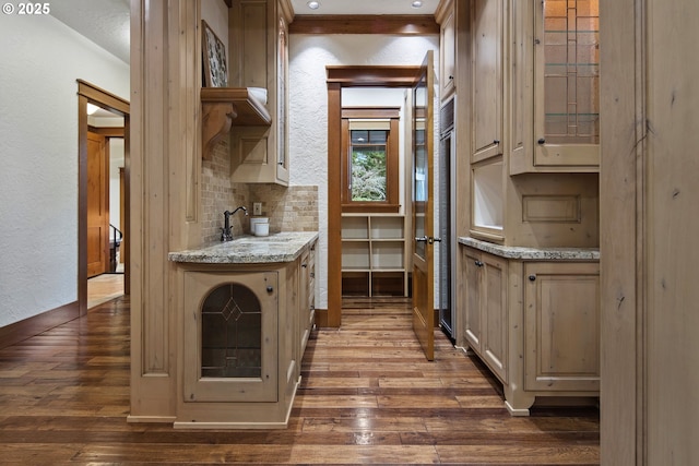 kitchen with sink, dark wood-type flooring, backsplash, light stone counters, and cream cabinetry