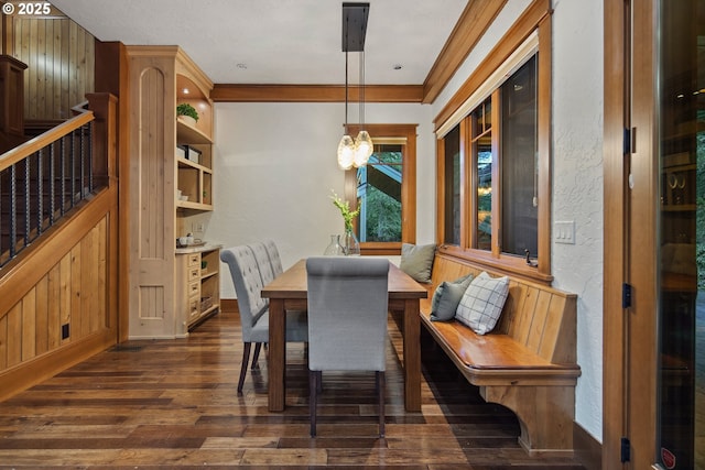 dining space featuring dark wood-type flooring, ornamental molding, and a chandelier