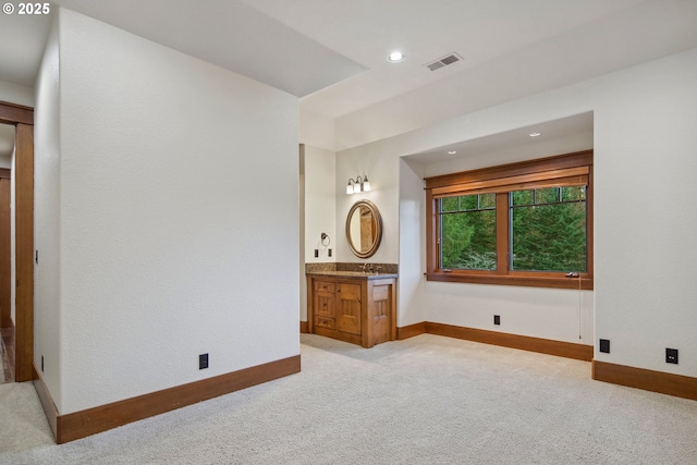 unfurnished bedroom with ensuite bath and light colored carpet