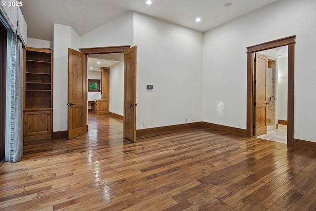 empty room with wood-type flooring and lofted ceiling