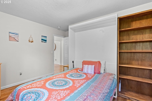 579 S Schooner Creek Rd, Lincoln City, OR 97367 - bedroom featuring baseboards, wood finished floors, and a textured ceiling