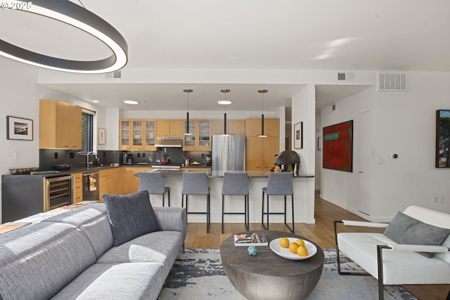 living room with light hardwood / wood-style floors and beverage cooler