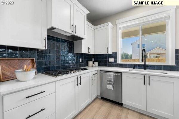 kitchen featuring decorative backsplash, sink, white cabinets, and stainless steel appliances